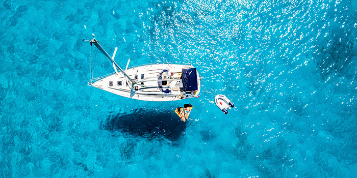 L'image montre un bateau se reposant paisiblement sur des eaux turquoise étincelantes, évoquant une journée estivale parfaite en pleine mer.