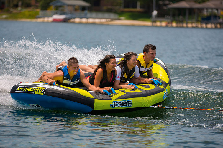 Amis sur un lac : activité estivale en bouée tractée, éclaboussures et rires sous le soleil.