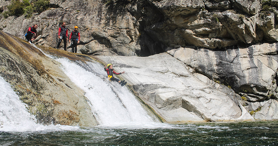 aventure-de-canyoning-en-pleine-nature-avec-des-amis Cette image illustre un groupe d'amis pratiquant le canyoning en harmonie avec la nature, glissant sur des rochers et surplombant des chutes d'eau, entourés de végétation luxuriante.