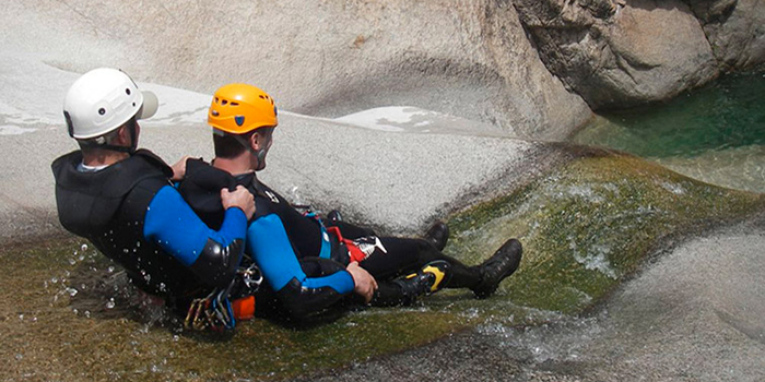 Deux aventuriers dévalent une rivière cristalline en canyoning, créant des éclaboussures et vibrant d'adrénaline, avec la nature comme toile de fond.