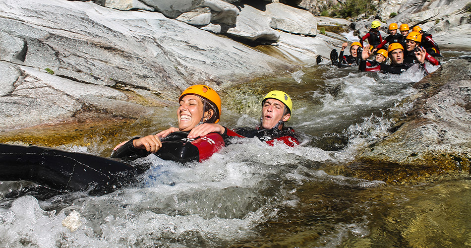 aventure-de-canyoning-en-pleine-nature-avec-des-amis Des aventuriers traversent une rivière tumultueuse lors d'une séance de canyoning, équipés de casques et de combinaisons, illustrant l'amusement en pleine nature.