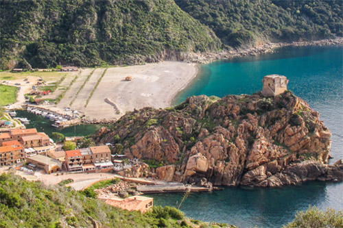 Photographie panoramique du Golfe de Porto en Corse avec un village côtier, des eaux cristallines et la tour emblématique. Atmosphère paisible sous un ciel bleu et montagnes verdoyantes.