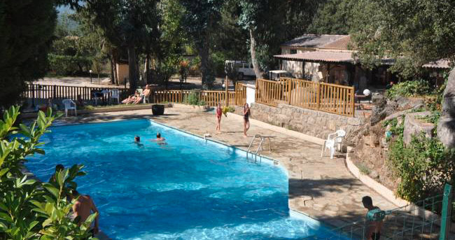 Piscine de camping entourée de verdure, où enfants et adultes profitent d'un moment estival de détente, rires et sérénité.