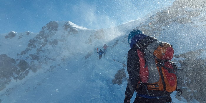 Expédition captivante de skieurs dans des montagnes enneigées sous un ciel bleu lumineux, capturant l'endurance et la quête d'aventure en haute nature.