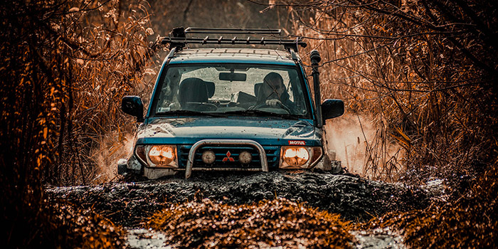 Un véhicule tout-terrain traverse une piste boueuse, illustrant l'aventure et l'exploration en pleine nature.
