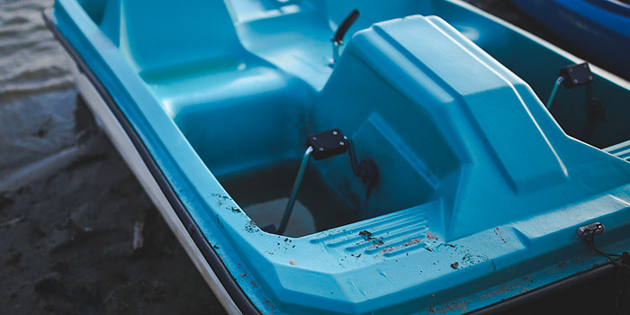 Pédalo bleu sur une rive évoquant l'été, loisirs et détente, reflétant l'appel à l'évasion dans un cadre naturel apaisant.