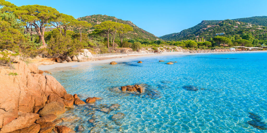Magnifique plage corse avec eaux claires et montagnes verdoyantes en arrière-plan