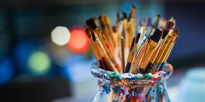 Pots de pinceaux colorés dans un atelier artistique, évoquant créativité et inspiration.