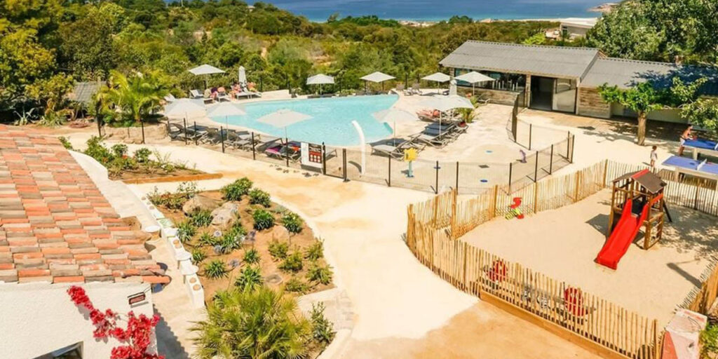 L'image montre des familles profitant de la piscine du Camping La Liscia, avec des enfants jouant sur l'aire de jeux et une vue sur la mer, parfait pour des vacances détendues.