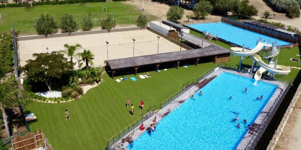 Espace aquatique animé avec piscines, toboggans, familles s'amusant, et cadre verdoyant idéal pour des souvenirs estivaux.