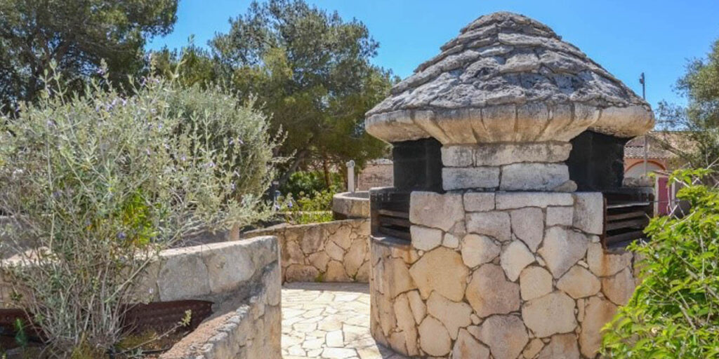 Cette image capture la beauté d'un barbecue en pierre, parfait pour les réunions estivales. Le jardin luxuriant et l'ambiance chaleureuse invitent à profiter des plaisirs gastronomiques en plein air, faisant rêver de délicieux moments partagés avec des proches.
