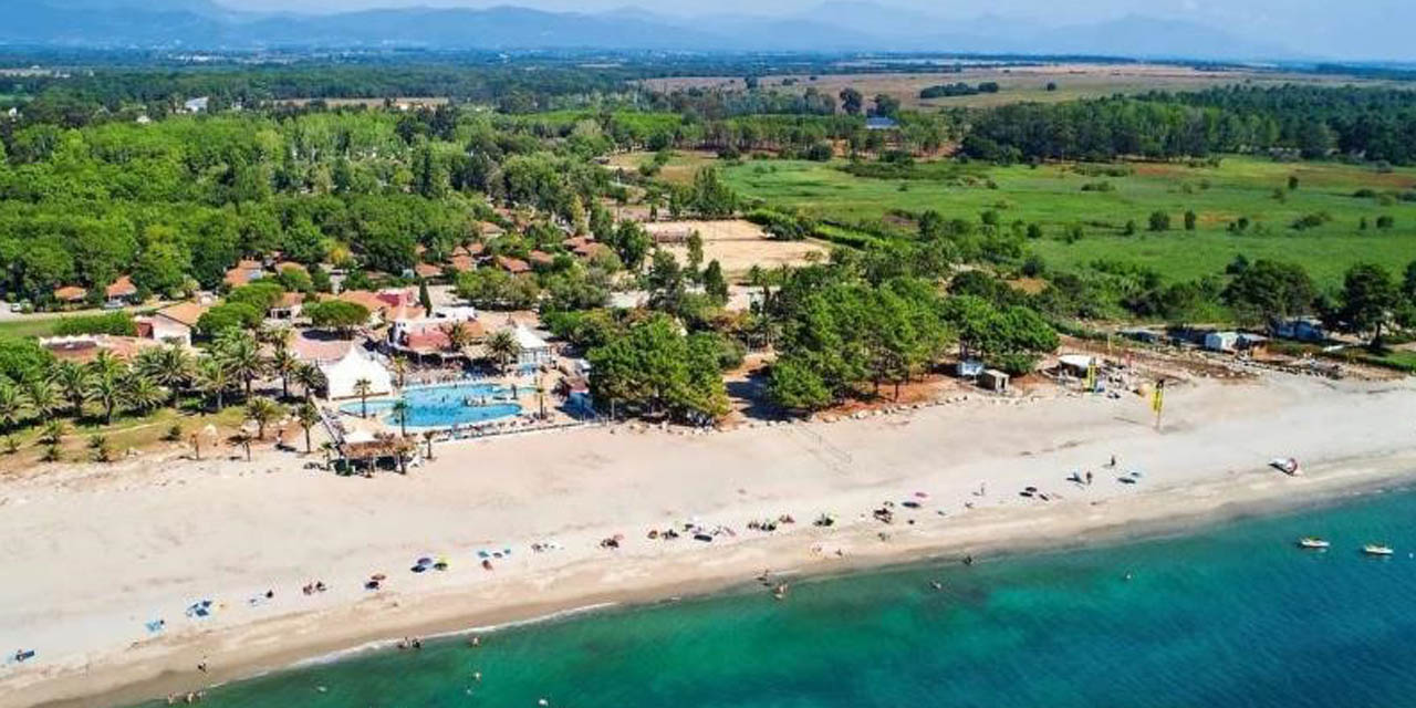 Image d'une plage lumineuse avec sable fin, mer turquoise, piscine entourée de palmiers, illustrant des vacances idéales.