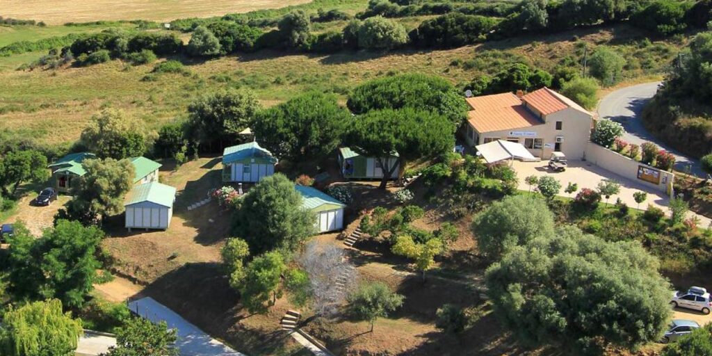 Cette image d'un camping en pleine nature évoque un séjour paisible, entouré de verdure et de tranquillité. La disposition harmonieuse des chalets et des arbres renforce l'idée d'une évasion relaxante, parfaite pour les amoureux de la nature en quête de sérénité.