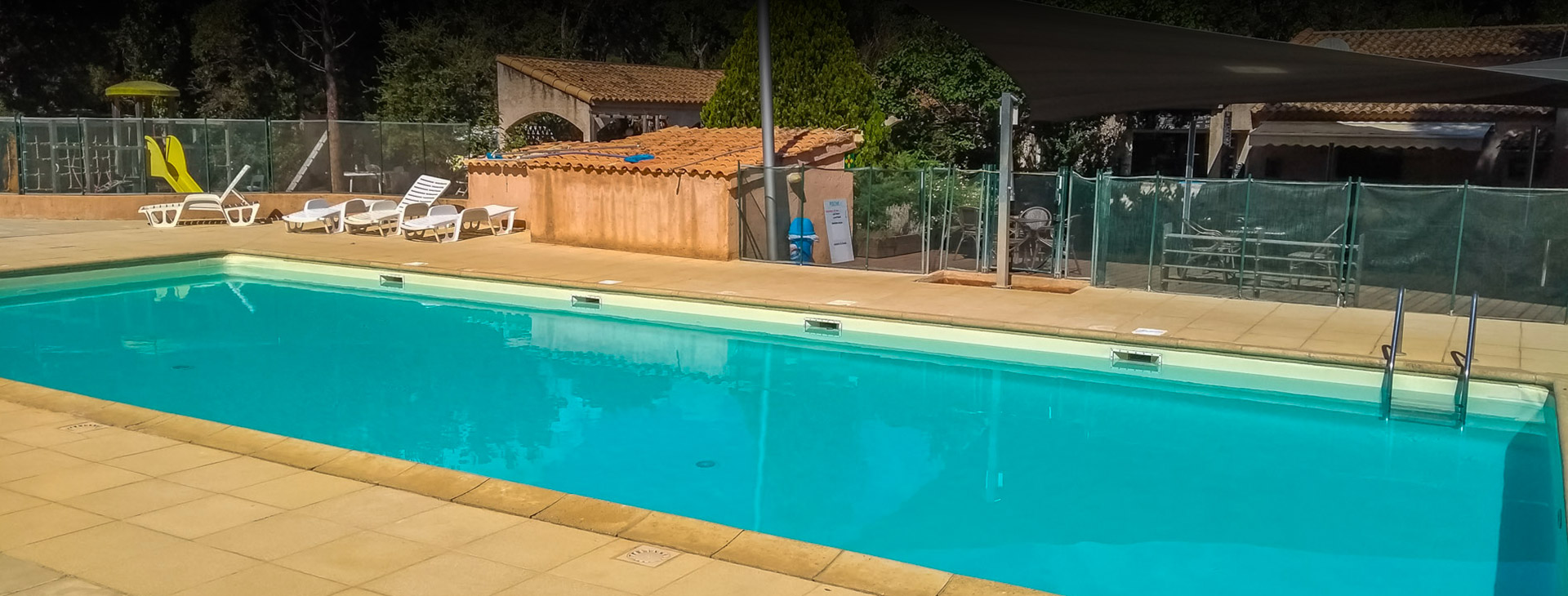 Piscine tranquille au camping Santa Lucia sous le soleil Cette image illustre une ambiance estivale paisible au camping Santa Lucia, idéale pour des vacances au bord de la piscine. Le ciel bleu, la présence de chaises longues et de parasols promettent détente et relaxation sous le soleil.