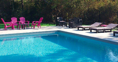 Détente au bord de la piscine dans un jardin ensoleillé Scène de relaxation estivale avec chaises longues colorées au bord d'une piscine scintillante entourée de verdure, parfait pour une journée ensoleillée.