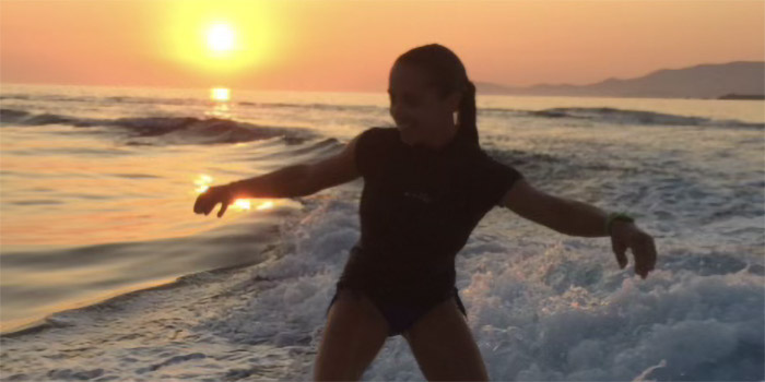 Jeune femme pratiquant le wakeboard sur une plage ensoleillée, capturant l'esprit d'aventure aquatique pendant un coucher de soleil vibrant.