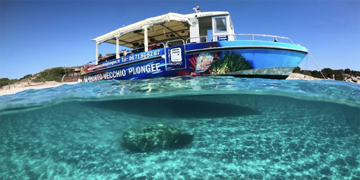 Image d'un bateau de plongée naviguant sur des eaux cristallines près de Porto Vecchio, offrant une escapade sereine et une occasion d'explorer la beauté sous-marine.