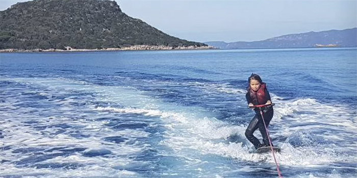 Une jeune surfeuse s'élançant audacieusement sur les vagues, symbolisant l'amour de l'aventure et de la liberté en mer.