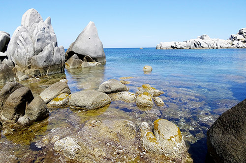Image de la plage des îles Lavezzi, montrant des rochers sculptés et des eaux cristallines sous un ciel bleu éclatant, évoquant une ambiance apaisante et sauvage.
