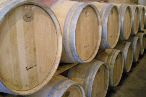 Barriques en bois alignées dans une distillerie artisanale, illustrant les traditions de la vinification et l'art du vieillissement.